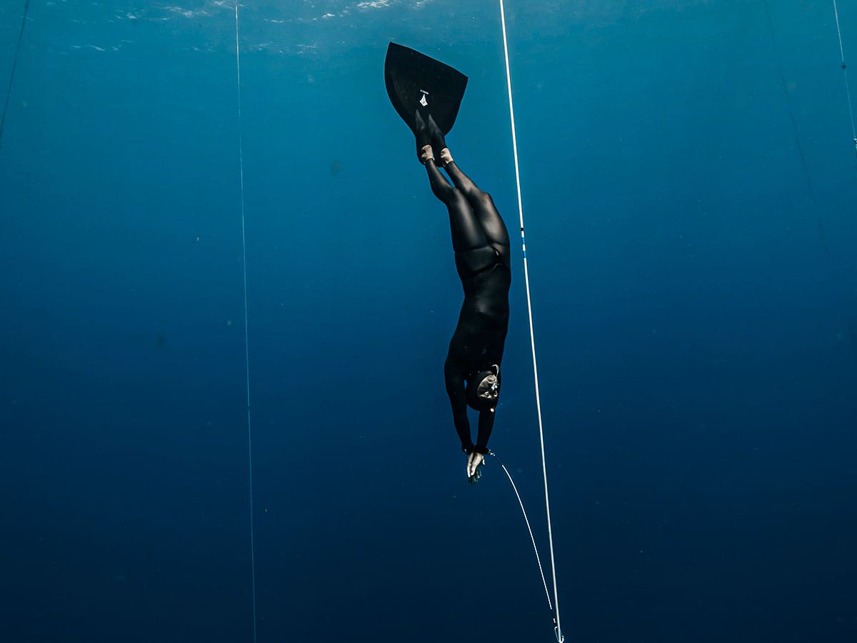 Freediver kicking head-first down a line with a single wide fin